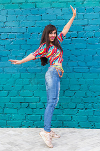 街舞、自由式和爵士放克概念 — 美丽的女孩在蓝砖墙上跳嘻哈