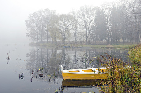 秋湖和晨雾上的黄色木船