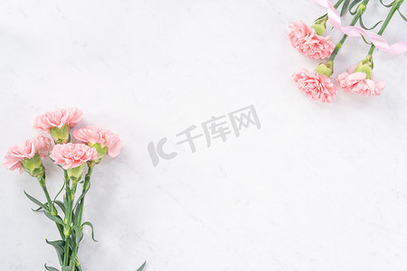优雅粉色摄影照片_明亮的白色大理石桌背景上美丽优雅的粉色康乃馨花，母亲节花礼的概念，顶视图，平躺，头顶