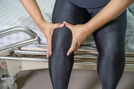 膝盖疼痛摄影照片_亚洲中年女病人触摸膝盖疼痛，健康的医疗理念。