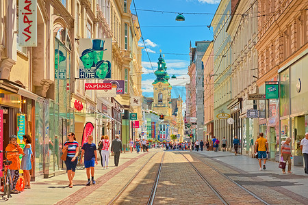 行走线路摄影照片_林茨 — 2020 年 6 月，奥地利：穿过城市的主要街道，步行的人、商店和电车线路