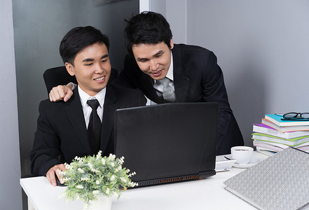 两个商人在使用笔记本电脑时大笑