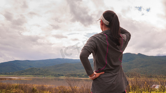 早上在大自然中跑步后，快乐的运动女性正在休息，看着风景。