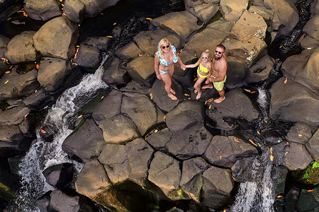 从高处看毛里求斯岛罗切斯特瀑布背景的一家人。热带毛里求斯岛丛林中的瀑布
