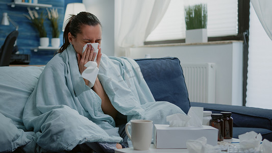 生病的女人用纸巾吹感冒流鼻涕