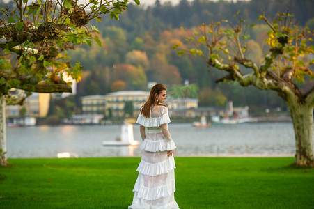 一位穿着白色婚纱的新娘在奥地利小镇的一个公园里，日落时有大树