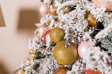圣诞树上装饰着金色和粉色的玩具。