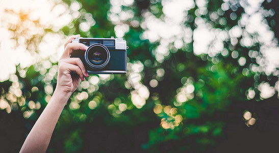 拍照价格单摄影照片_举起的手拿着旧相机拍照