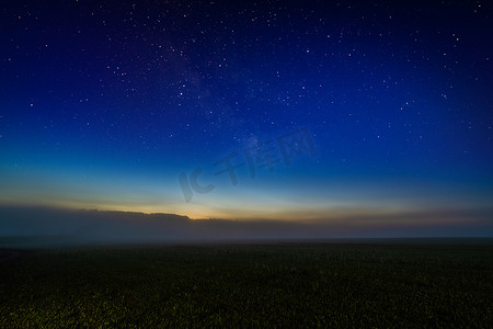 蓝色的星空背景摄影照片_有星空的有雾的夜场和余辉地平线梯度