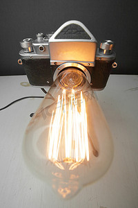 电商渐变背景摄影照片_来自旧相机的复古灯，灰色背景上有一盏爱迪生灯。