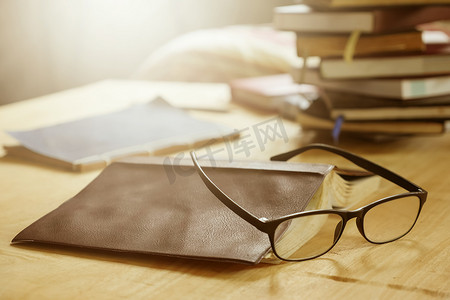 木空间摄影照片_木桌上有书的眼镜，柔和的焦点，耀斑阳光，复古色调。