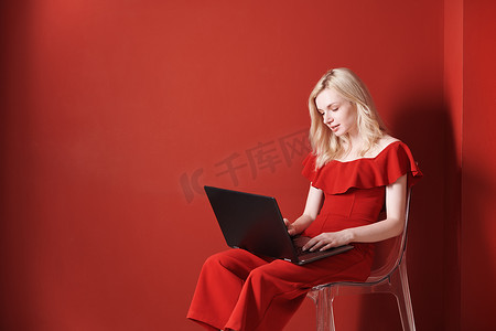 坐在椅子上并在笔记本电脑上工作的年轻成年女性