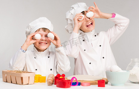 表彰形式摄影照片_拿着鸡蛋的厨师形式的小男孩和女孩