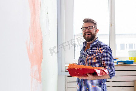 男人用油漆滚筒粉刷家里的内墙。