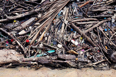 垃圾堆堆放树枝木、堆木头和塑料瓶废物和碎片漂浮在河水脏的水面上、海滩或河流的垃圾污染和环境问题