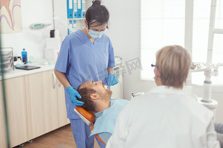 医疗清洁摄影照片_医疗护士为男病人进行专业牙齿清洁