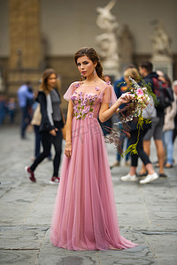 捧花的女孩摄影照片_意大利佛罗伦萨老城中心，身穿粉色连衣裙、捧花的新娘站立