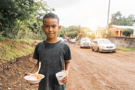 在当地庆祝活动中，尼加拉瓜男孩拿着一盘 nacatamal 和一杯咖啡