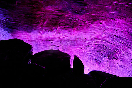 紫色的光芒摄影照片_艺术展示中带有岩石轮廓的紫色光芒