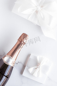 大理石上的香槟瓶和礼盒、新年、圣诞节、情人节或婚礼节日礼物以及饮料品牌的奢侈品包装