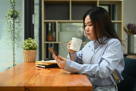 亚洲女员工在公司办公室喝咖啡休息并使用手机