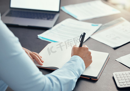 女性在办公桌办公室的纸质笔记本上写笔记、日程安排和计划想法、预算和交易分析。