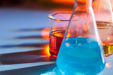 发光的实验室烧瓶，里面装满了五颜六色的化学溶液，桌子上有阴影。