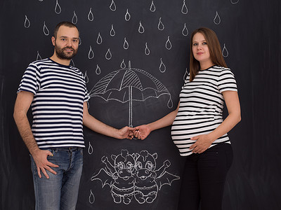 怀孕的夫妇在粉笔板上画出他们的想象力