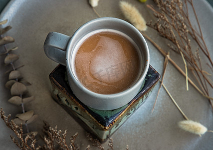 蓝色陶瓷杯中的热橙奶茶、陶瓷上的甜茶点泰式奶茶和陶瓷盘上的干花。