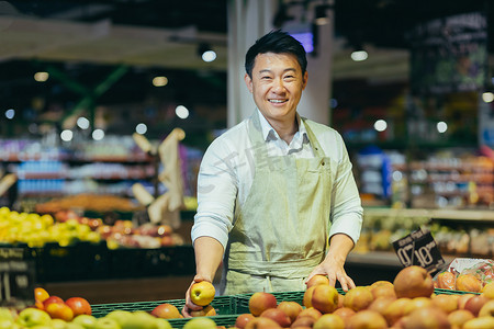 亚洲超市销售员的肖像，杂货蔬菜区的男子微笑着看着镜头