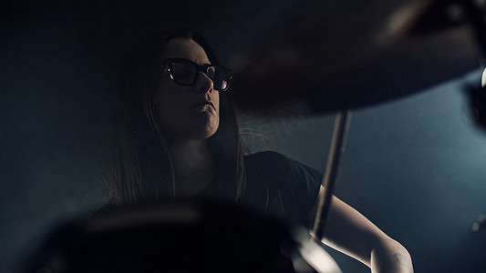 戴眼镜的年轻女鼓手演奏架子鼓