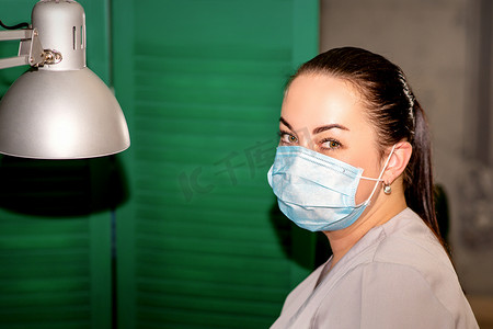 戴着防护面罩的年轻女足病医生在她的足病诊所里看着镜头。