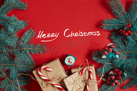 圣诞节背景绿色摄影照片_冷杉树枝和礼品盒在红色背景。