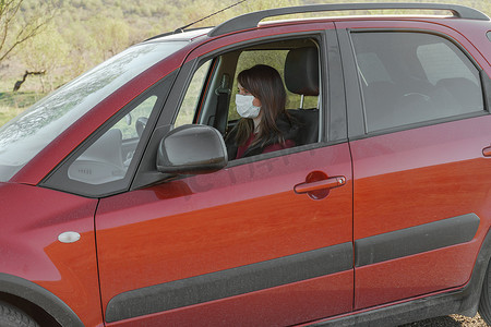 孩坐摄影照片_戴医用口罩和手套的女孩坐在驾驶座的车里
