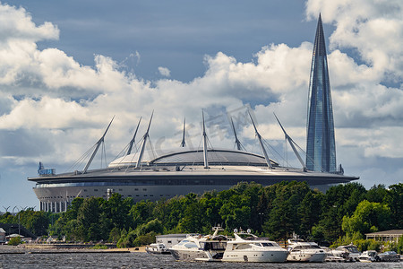天然气公司摄影照片_俄罗斯，圣彼得堡，2022年7月29日：俄罗斯天然气工业股份公司竞技场足球场新楼、帆船和摩托艇停泊在路堤附近，天然气公司俄罗斯天然气工业股份公司的摩天大楼Lakhta