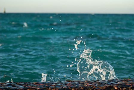 美丽清澈的绿松石海水表面的照片特写，海景背景上有波纹和明亮的飞溅，水平图片
