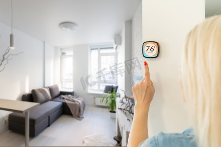 自动化控制摄影照片_墙上的恒温器智能家居家庭自动化控制面板，用于冬季房屋温度横幅全景。