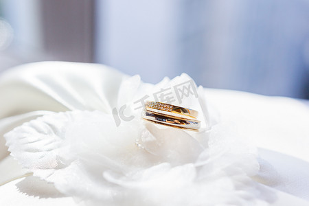 白色丝绸织物上镶有钻石的金色结婚戒指。