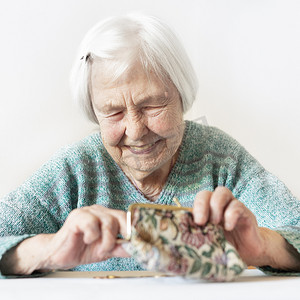 开朗的 96 岁老妇人坐在家里的餐桌旁，支付账单后，她对钱包里的养老金储蓄感到满意。
