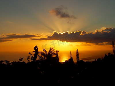 从坦塔罗斯山看到的日落穿过海洋上的云层，经过热带树木的剪影