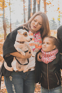 女孩抱着摄影照片_母亲和女儿在秋天的公园里，女孩抱着她的杰克罗素梗犬。
