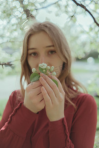 金发碧眼的红衣女孩呼吸着樱花的香味