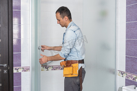 淋浴房详情页摄影照片_工人们正在淋浴房的玻璃门上安装硅胶密封垫。