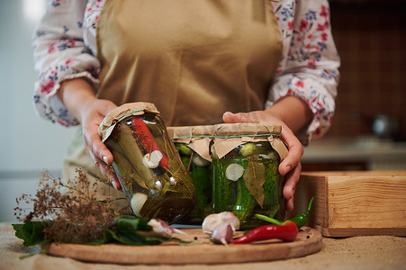 细节：家庭主妇的手向镜头展示自制罐头食品、泡菜和腌制辣椒