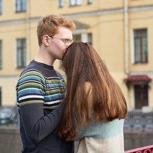 红头发的男人亲吻了一个女人的头顶，一个穿着毛衣的男孩安慰着一个长着深色浓密头发的女孩