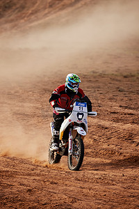 骑摩托车赛车摄影照片_在沙漠拉力赛上骑越野摩托车的车手。
