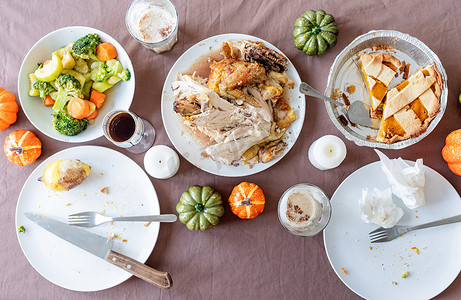 年终尾牙盛宴摄影照片_盛宴、剩菜和脏盘子后感恩节餐桌的顶视图