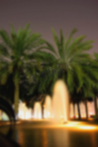 模糊背景街道喷泉、棕榈树晚间灯光