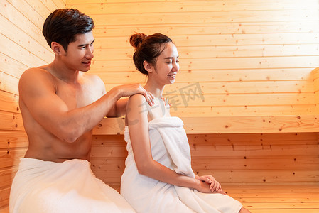 年轻的亚洲夫妇在桑拿房享受浪漫的放松按摩。