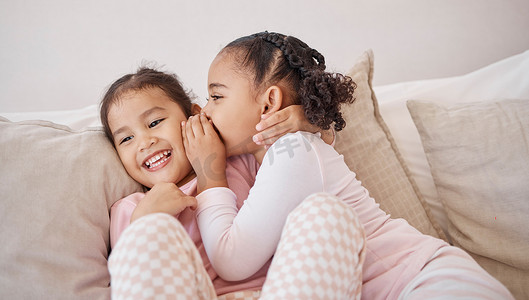 女孩、朋友或孩子在家里的沙发上向最好的朋友窃窃私语，同时在玩耍时一起放松。